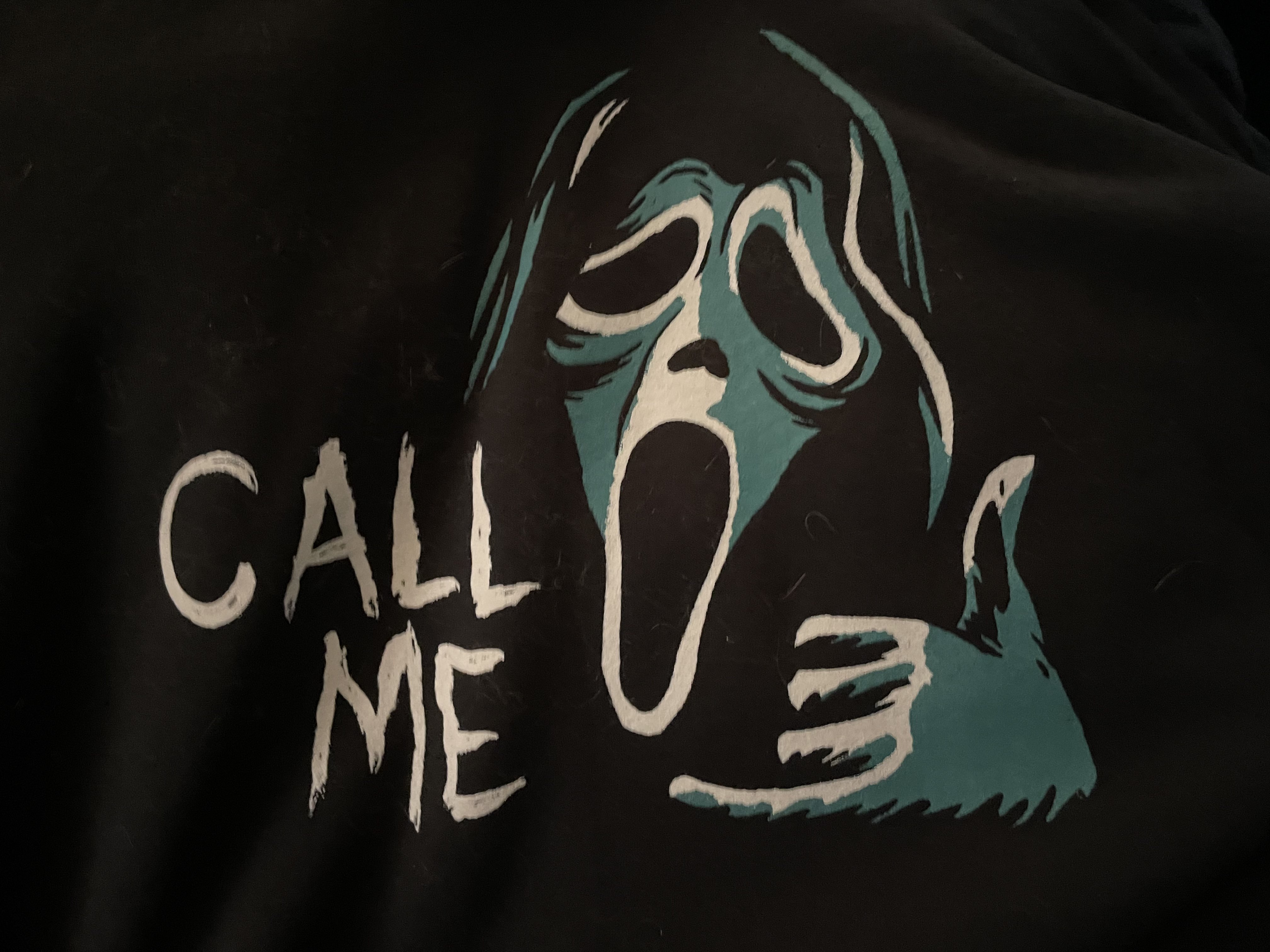 AN IMAGE OF THE PRINT ON MY GHOSTFACE HOODIE. GHOSTFACE IS HOLDING UP THE 'PHONE' SIGN WITH HIS HAND TO HIS EAR. IT'S CAPTIONED 'CALL ME'.